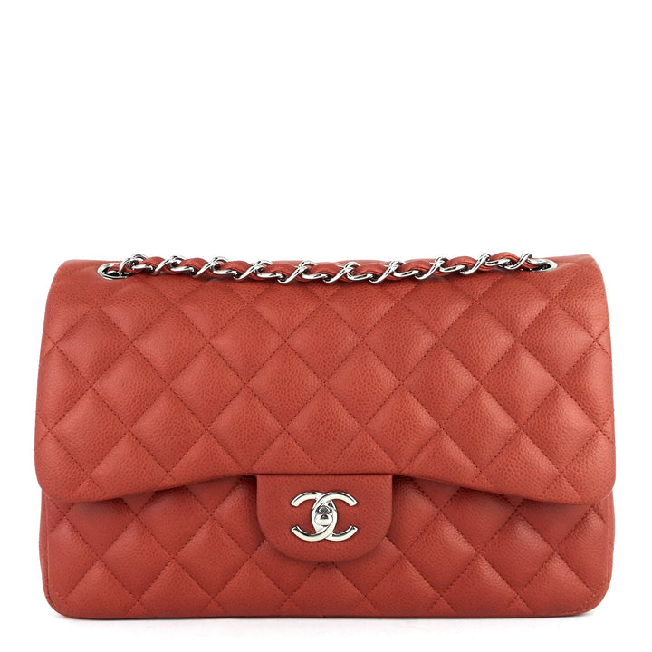 Red quilted handbag with silver chain and clasp on a white background