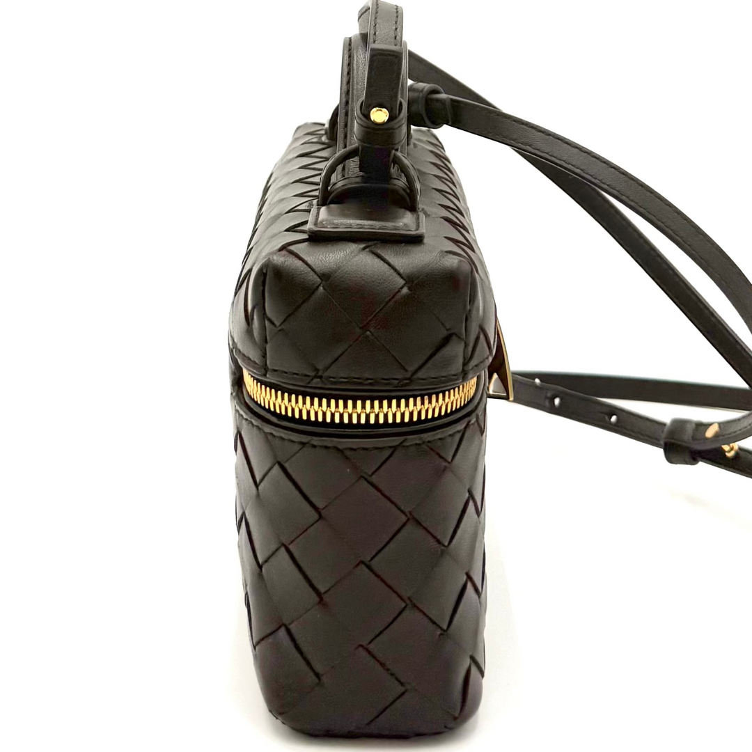 Black quilted handbag with a gold zipper on a white background