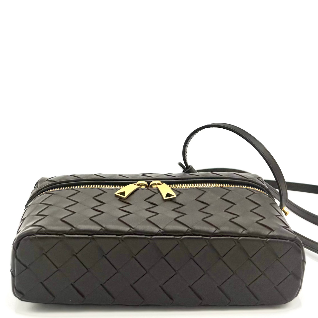 Black woven handbag with a gold zipper on a white background