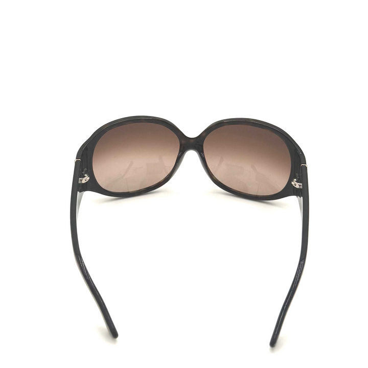Oversized oval sunglasses with a black frame and brown gradient lenses, shown from the back on a white background.