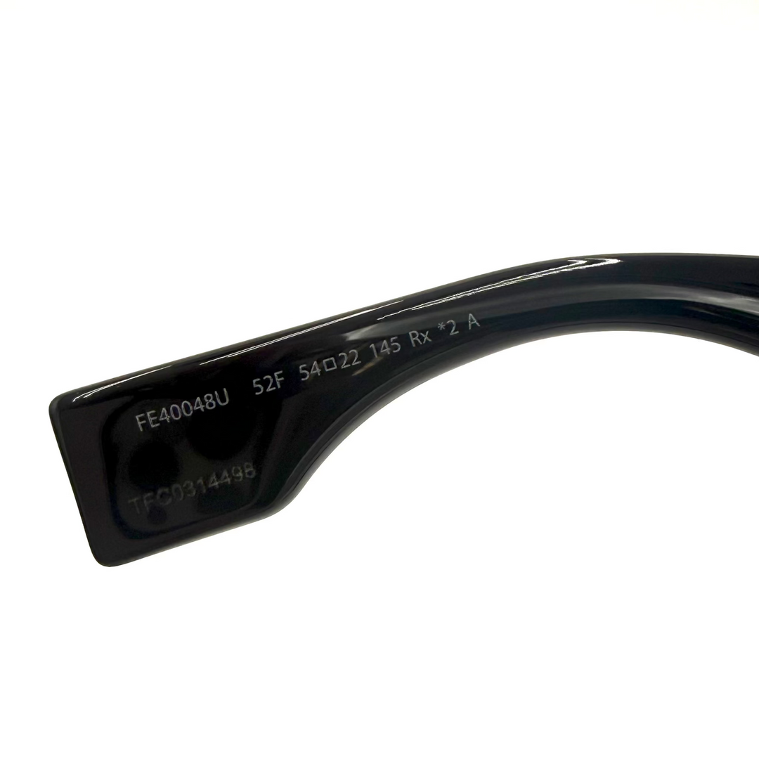 Close-up of the inner temple arm of a pair of black sunglasses, showing printed model and frame details on a white background.