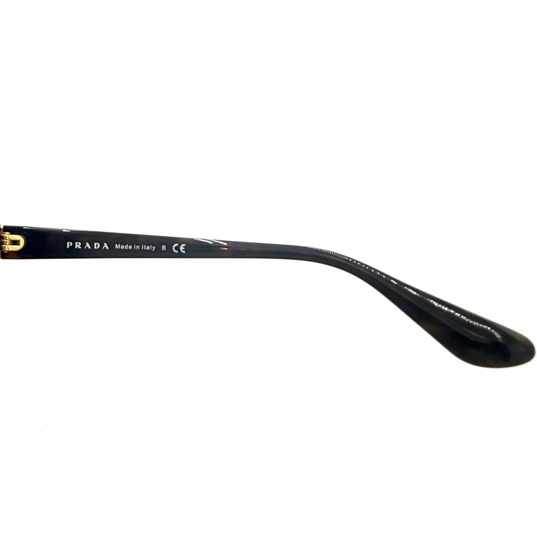 A close-up of a Prada sunglasses arm showing the inner temple with 'PRADA Made in Italy' printed in white on a glossy black finish, with a gold 'P' logo on the outer edge, set against a plain white background.