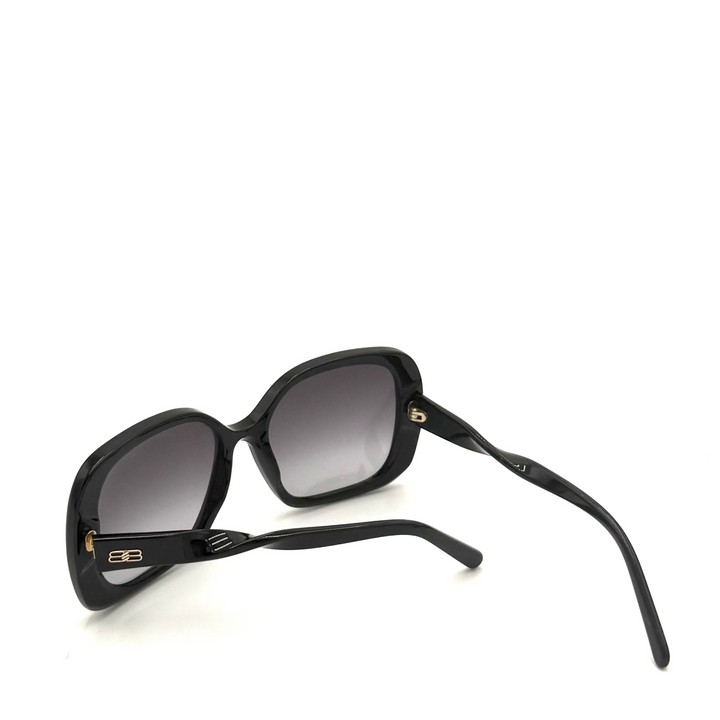 Black sunglasses laying on white table with one arm extended.