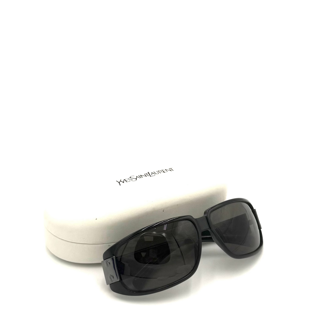 Black Yves Saint Laurent sunglasses with dark lenses, shown in front of their white hard case on a white background.