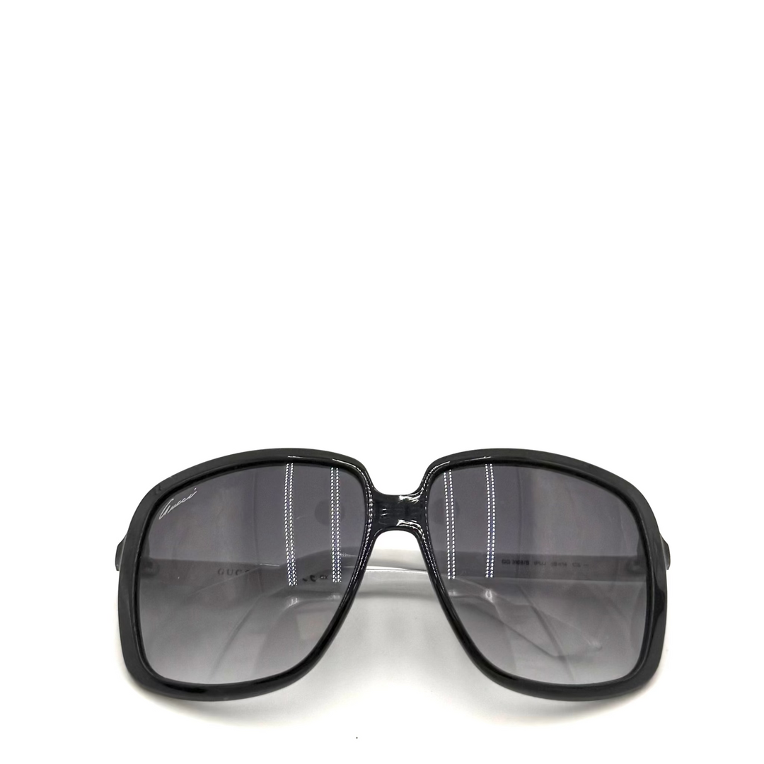 A pair of oversized square sunglasses with a thick black frame and dark gray gradient lenses, shown against a plain white background.