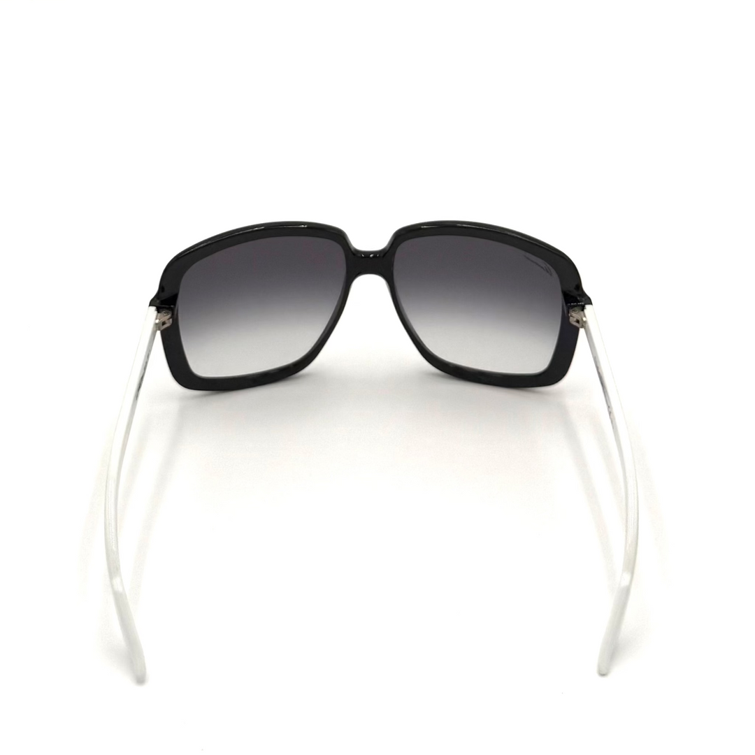 A pair of oversized square sunglasses with a glossy black frame and gradient gray lenses, featuring clear temples with small silver metal accents.