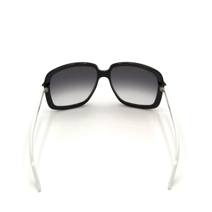 A pair of oversized square sunglasses with a glossy black frame and gradient gray lenses, featuring clear temples with small silver metal accents.