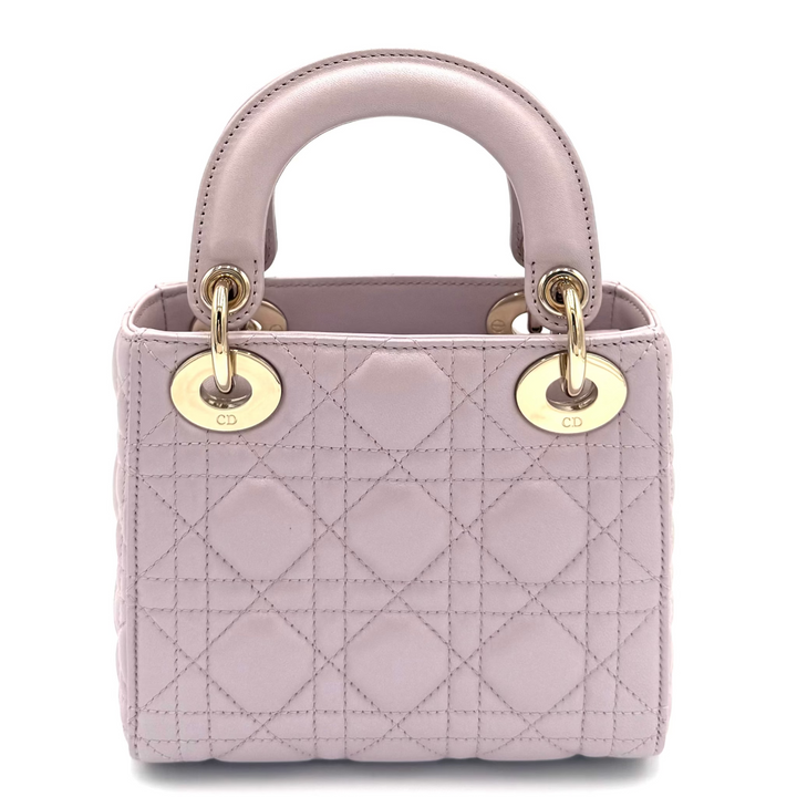 A light pink quilted leather handbag with a top handle, gold-tone hardware, and 'CD' logo medallions, photographed on a clean white background.