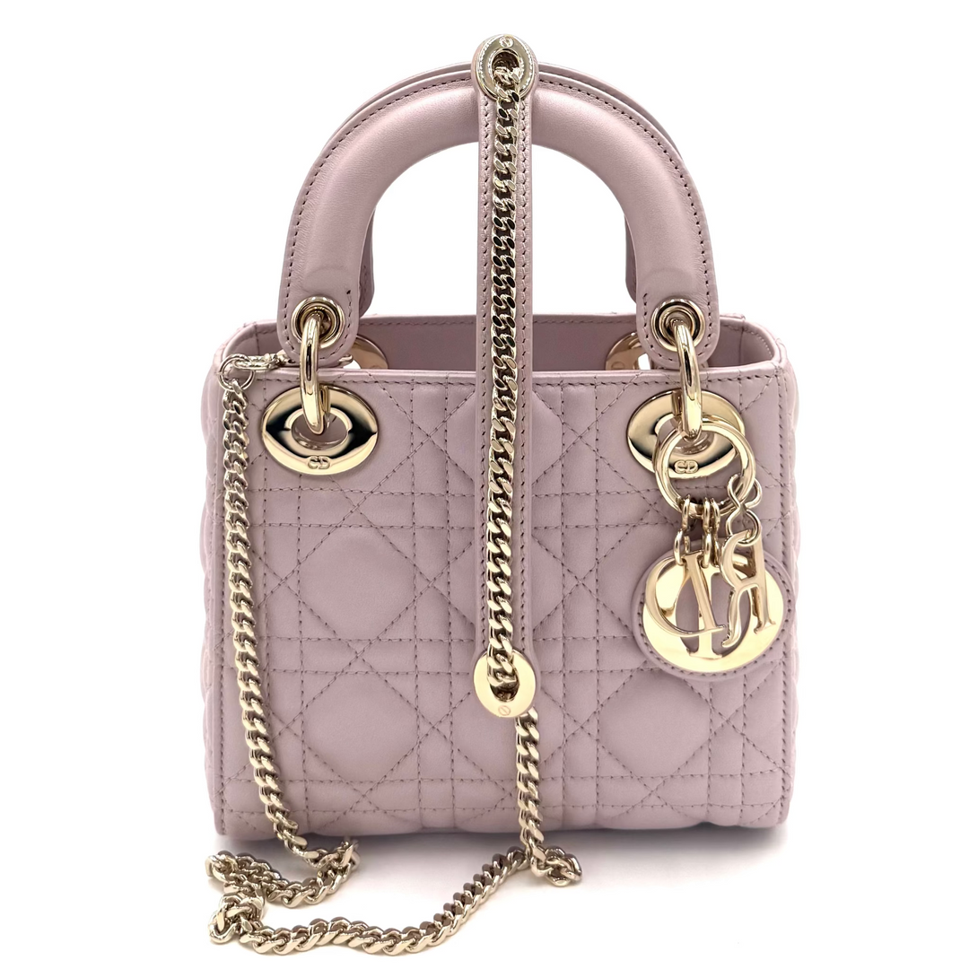 A small quilted top-handle handbag in pale pink leather with gold-tone chain strap and hardware, photographed against a bright white background.