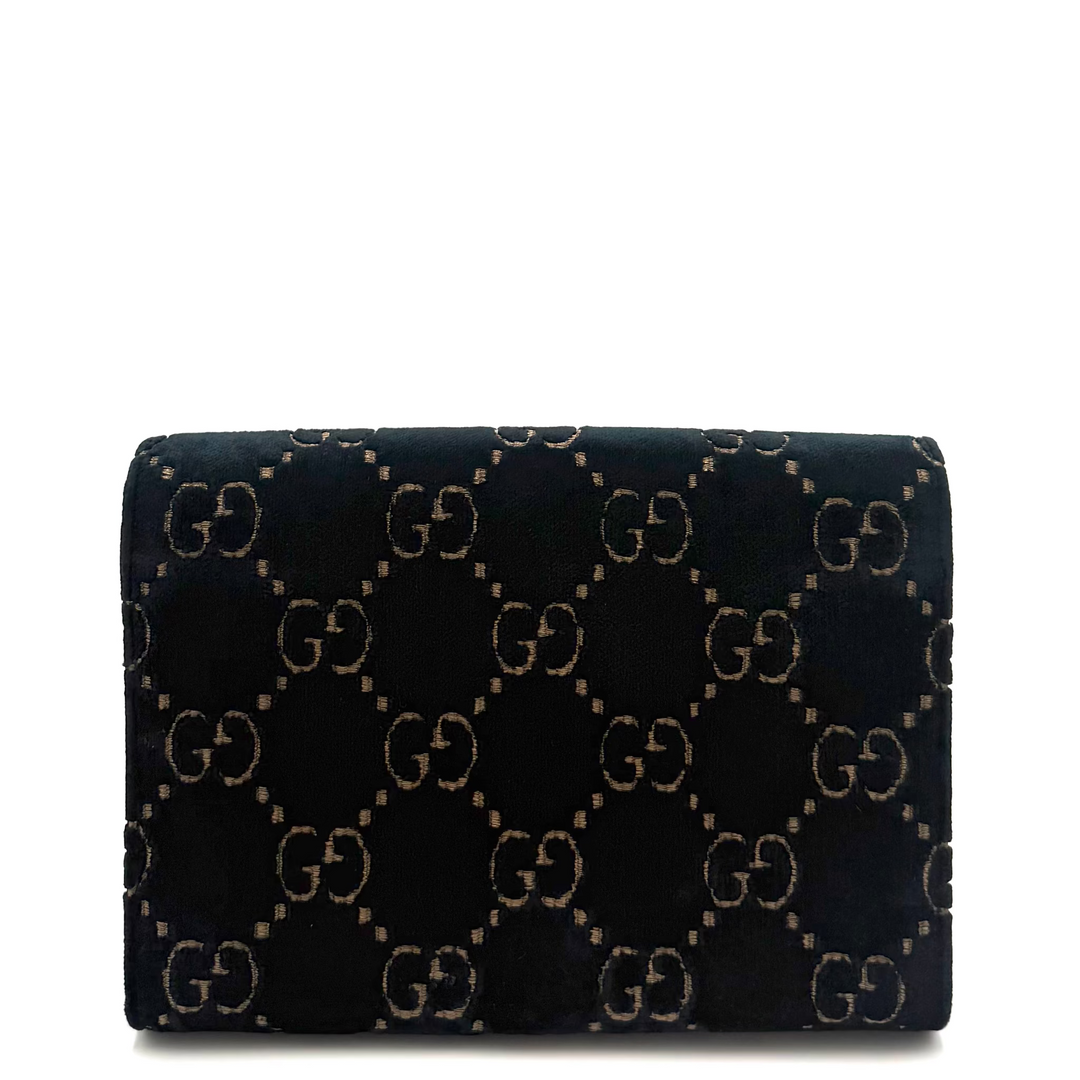 A black velvet Gucci clutch bag featuring the signature interlocking GG monogram pattern in beige, set against a plain white background.