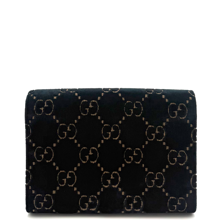 A black velvet Gucci clutch bag featuring the signature interlocking GG monogram pattern in beige, set against a plain white background.