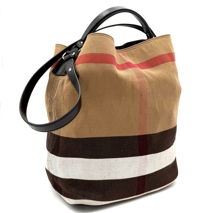 A vintage-style canvas bucket bag with a tan body, brown and white stripes, and a red stripe detail, featuring black leather handles, photographed inside a white lightbox studio.