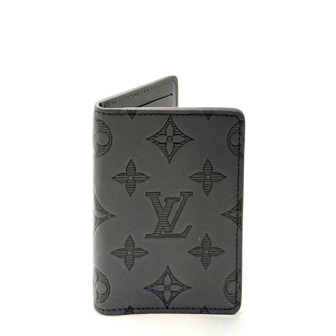 A dark gray Louis Vuitton monogram card holder standing upright on a white background.