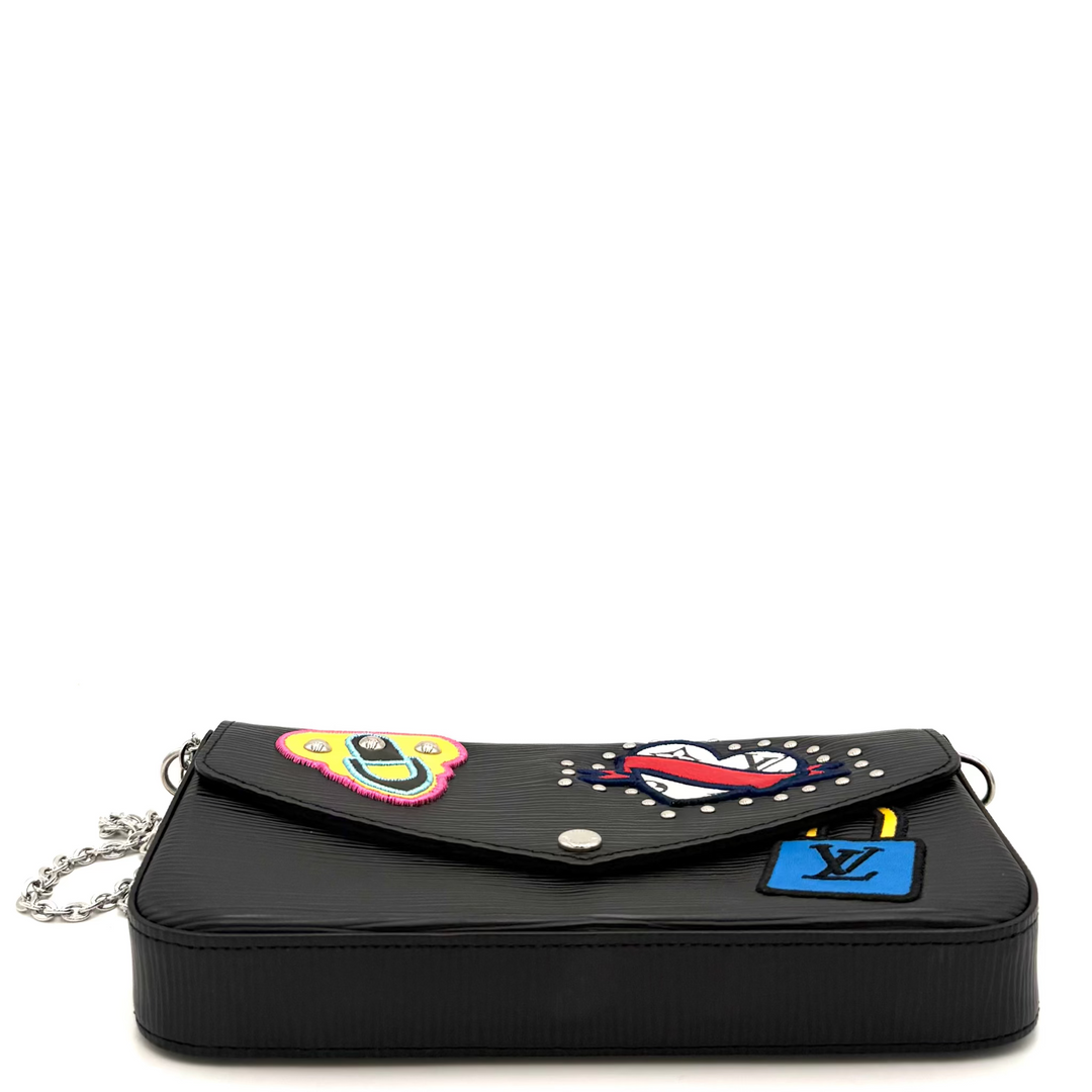 A black leather crossbody bag with a flap decorated with colorful embroidered patches and a blue Louis Vuitton monogram patch, shown on a white background.
