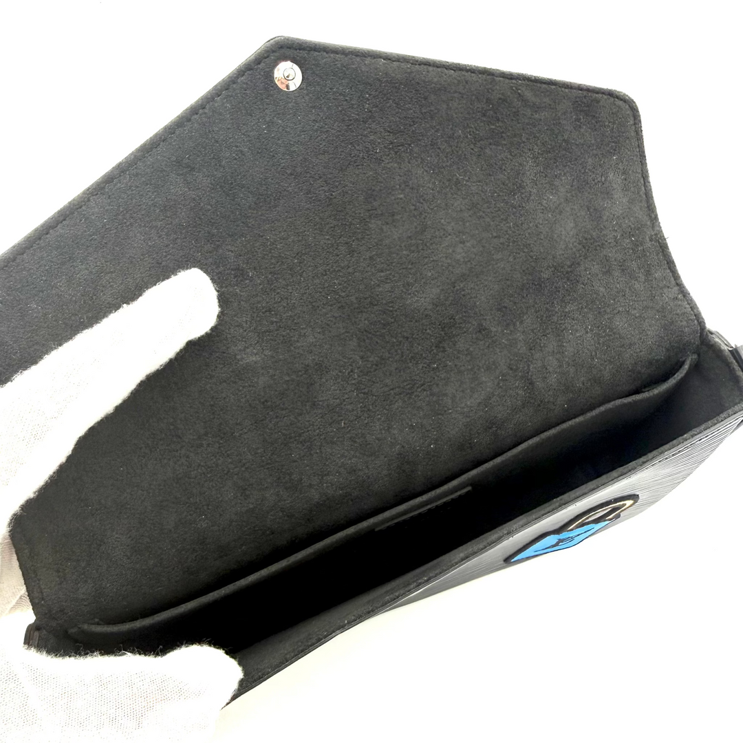 A black suede or nubuck wallet or card holder shown open, with a white-gloved hand holding it against a plain white background.
