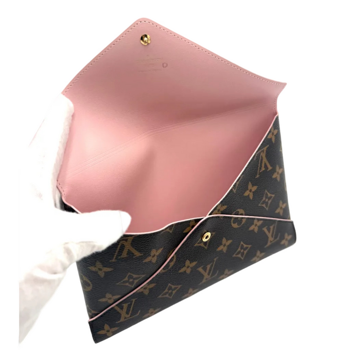 A Louis Vuitton envelope clutch bag in brown monogram canvas with a light pink leather interior, held open by a white gloved hand against a white background.