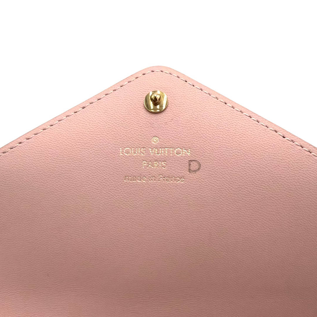 Close-up of a pink leather Louis Vuitton envelope-style pouch with gold-tone hardware and embossed Louis Vuitton Paris branding.