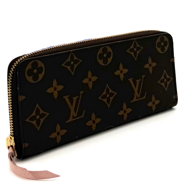 A Louis Vuitton monogram zip-around wallet in dark brown coated canvas with gold-tone hardware and a pink fabric pull tab, photographed on a white studio background.