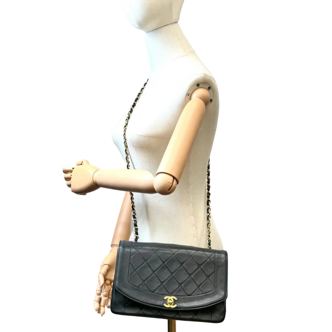 A black quilted leather shoulder bag with a gold CC turn-lock closure and chain strap, displayed on a white mannequin torso against a white background.