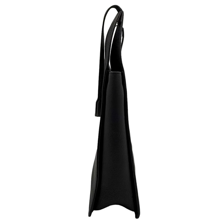 A black leather tote bag standing upright inside a white lightbox with silver reflective walls and bright overhead LED lights.