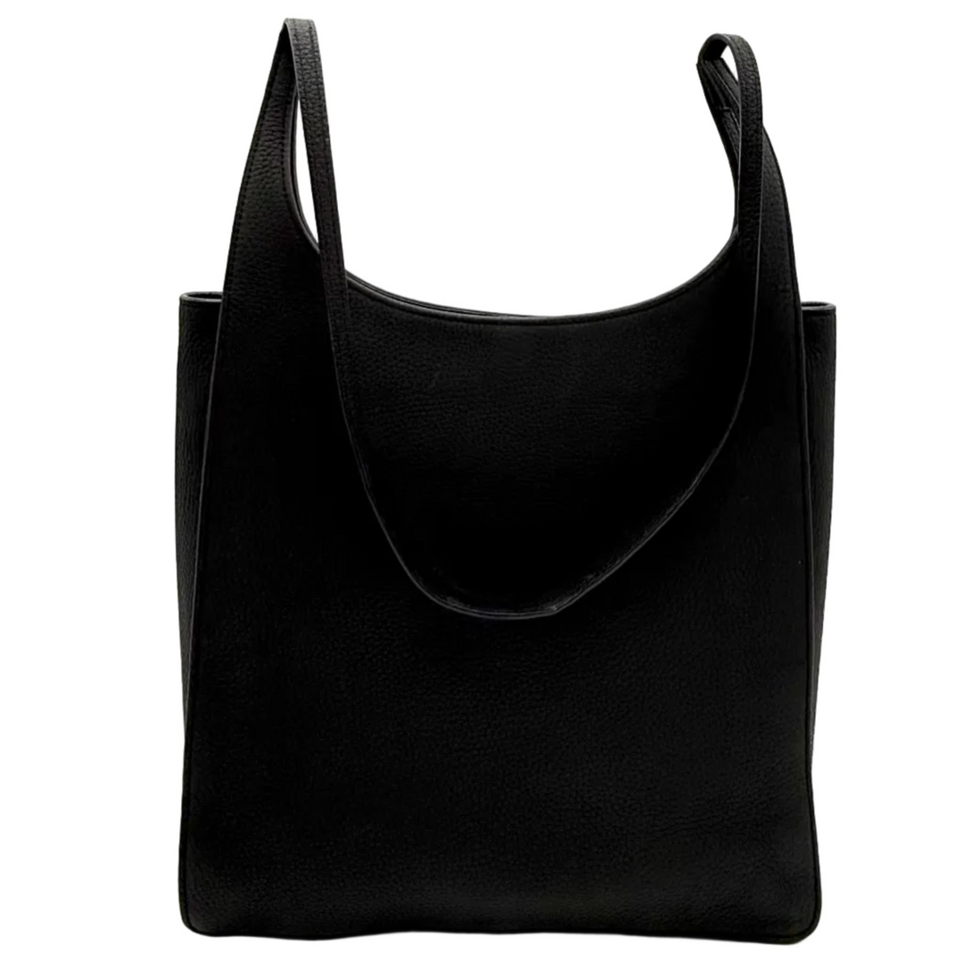 A black leather slouchy shoulder bag with wide straps, photographed inside a white lightbox studio setup with bright overhead lights.