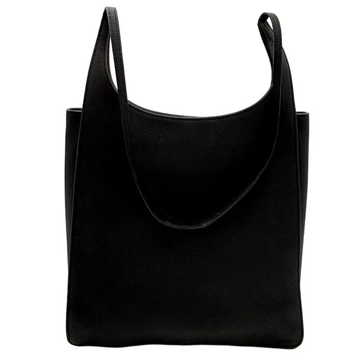A black leather slouchy shoulder bag with wide straps, photographed inside a white lightbox studio setup with bright overhead lights.