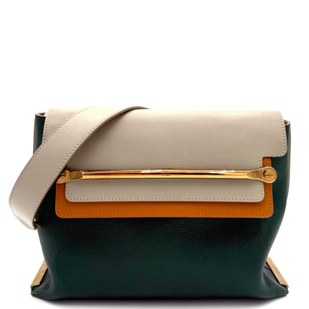 A structured leather shoulder bag with a color-blocked design featuring a dark forest green base, a cream flap, a cream horizontal band, and a bright orange accent panel, accented by a gold-tone bar and a matching cream strap.