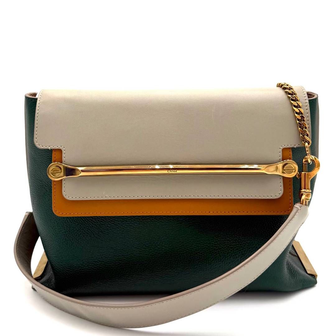 A color-blocked leather shoulder bag with a dark green base, a cream flap, a tan leather band, and gold-tone hardware, including a gold chain strap.