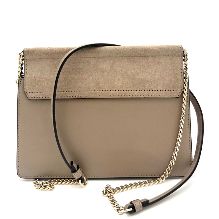A taupe suede and leather crossbody handbag with a gold chain strap, displayed on a clean white background.