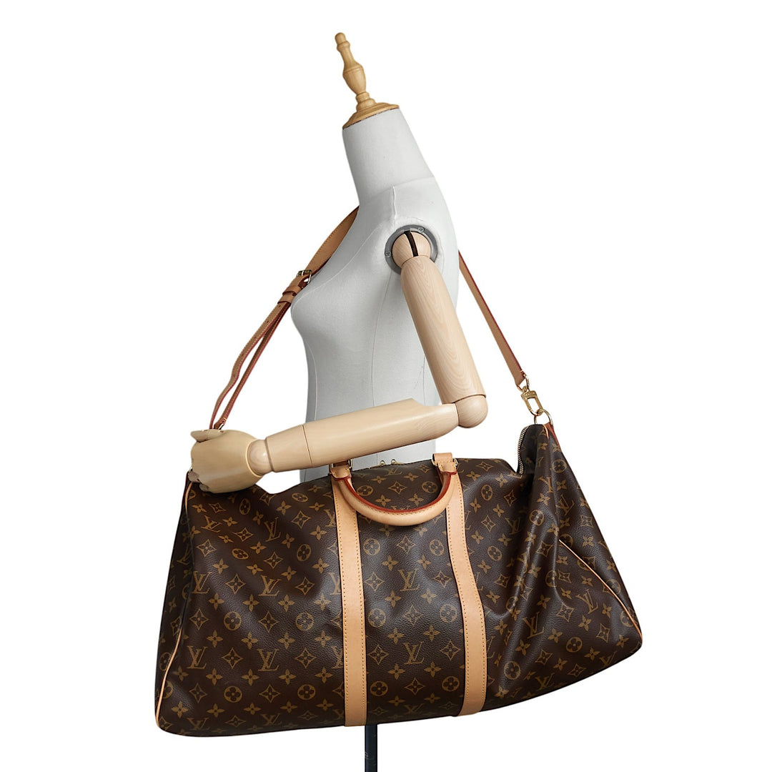 A Louis Vuitton monogram coated canvas duffel bag with tan leather trim and handles, displayed on a white mannequin torso against a white background.