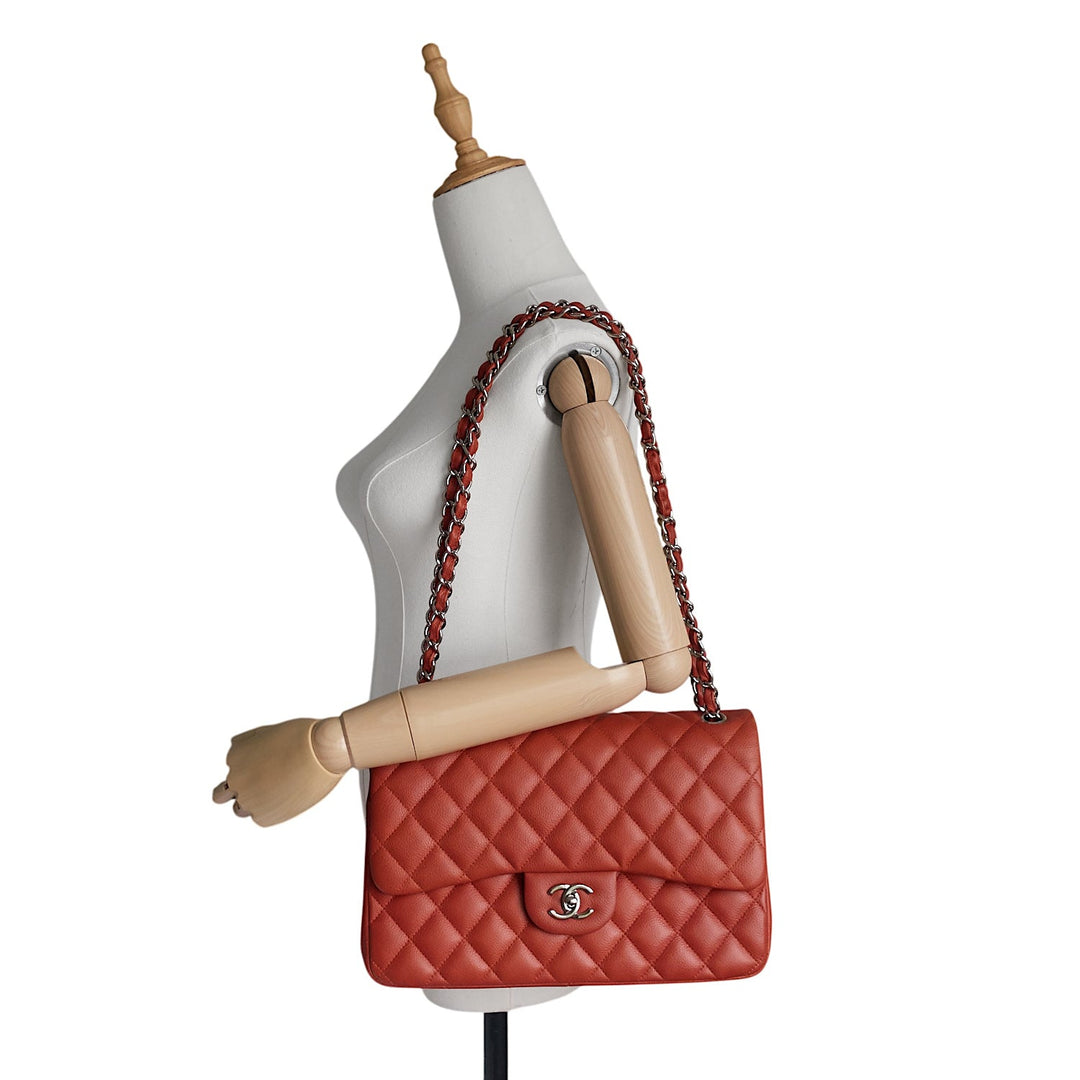 A red quilted leather shoulder bag with a silver-tone interlocking CC logo, displayed on a white mannequin torso against a white background.